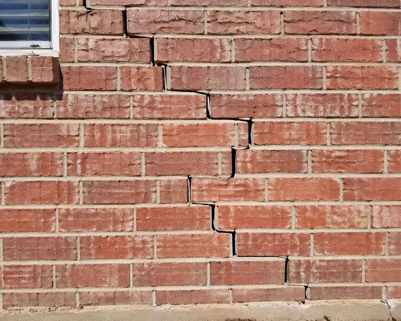 Stair-step cracks in a Dallas brick wall caused by expansive soil, requiring professional masonry repair Dallas TX.