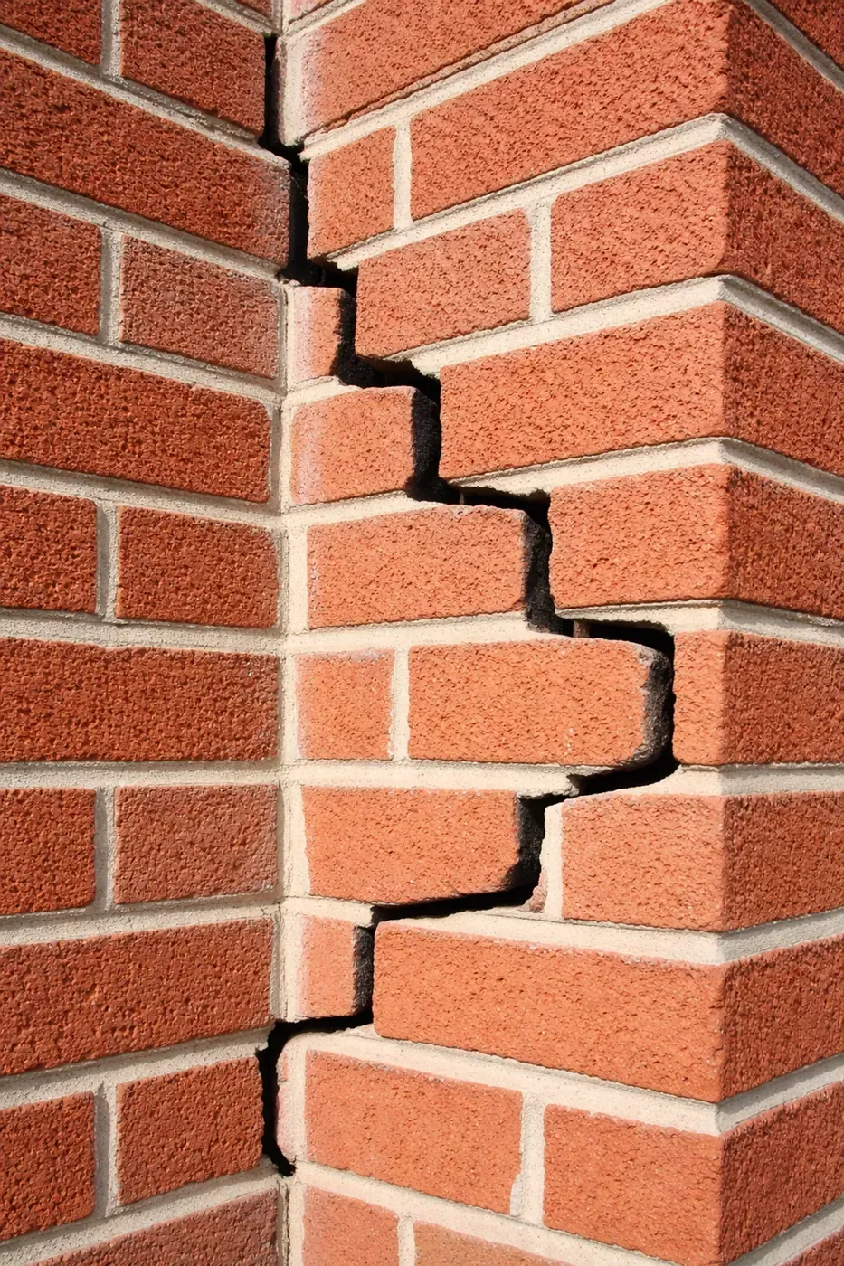 Detailed view of stair-step cracking in brick wall corner, a common sign of garage lintel failure in DFW homes.