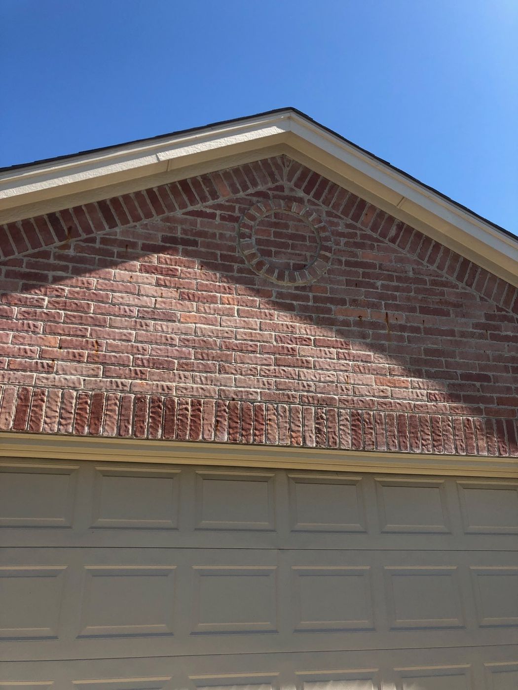 Decorative brick wall above garage door with circular inlay