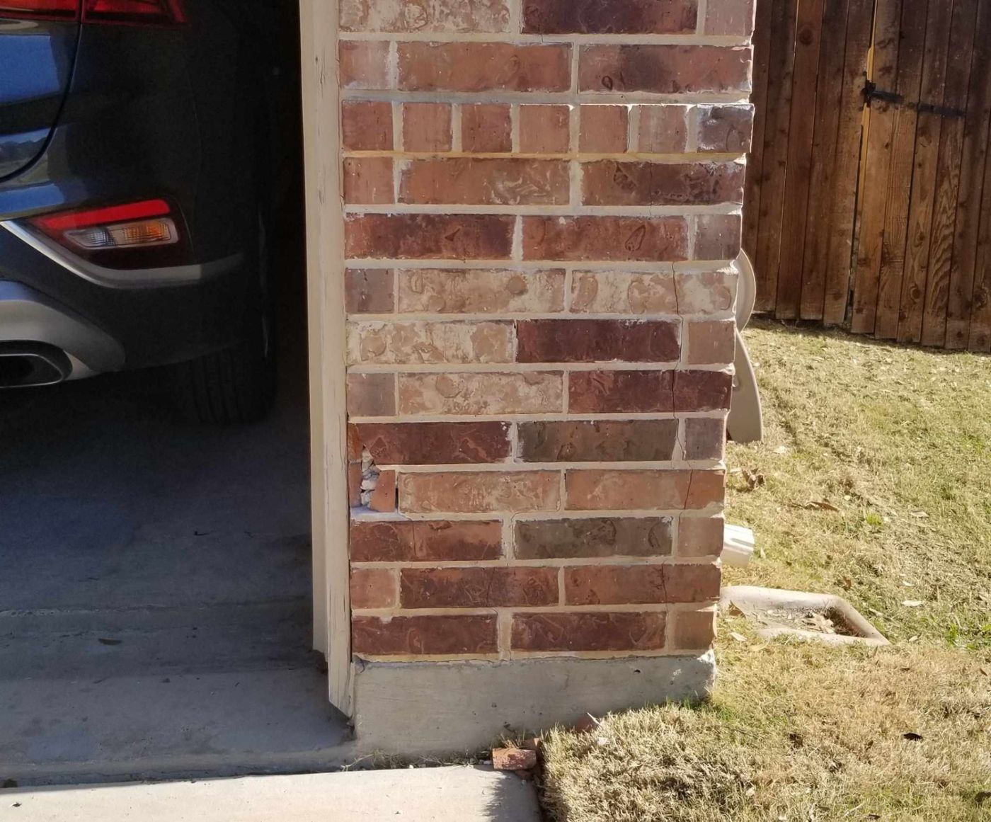 Damaged brickwork at a garage corner with visible cracking and missing brick