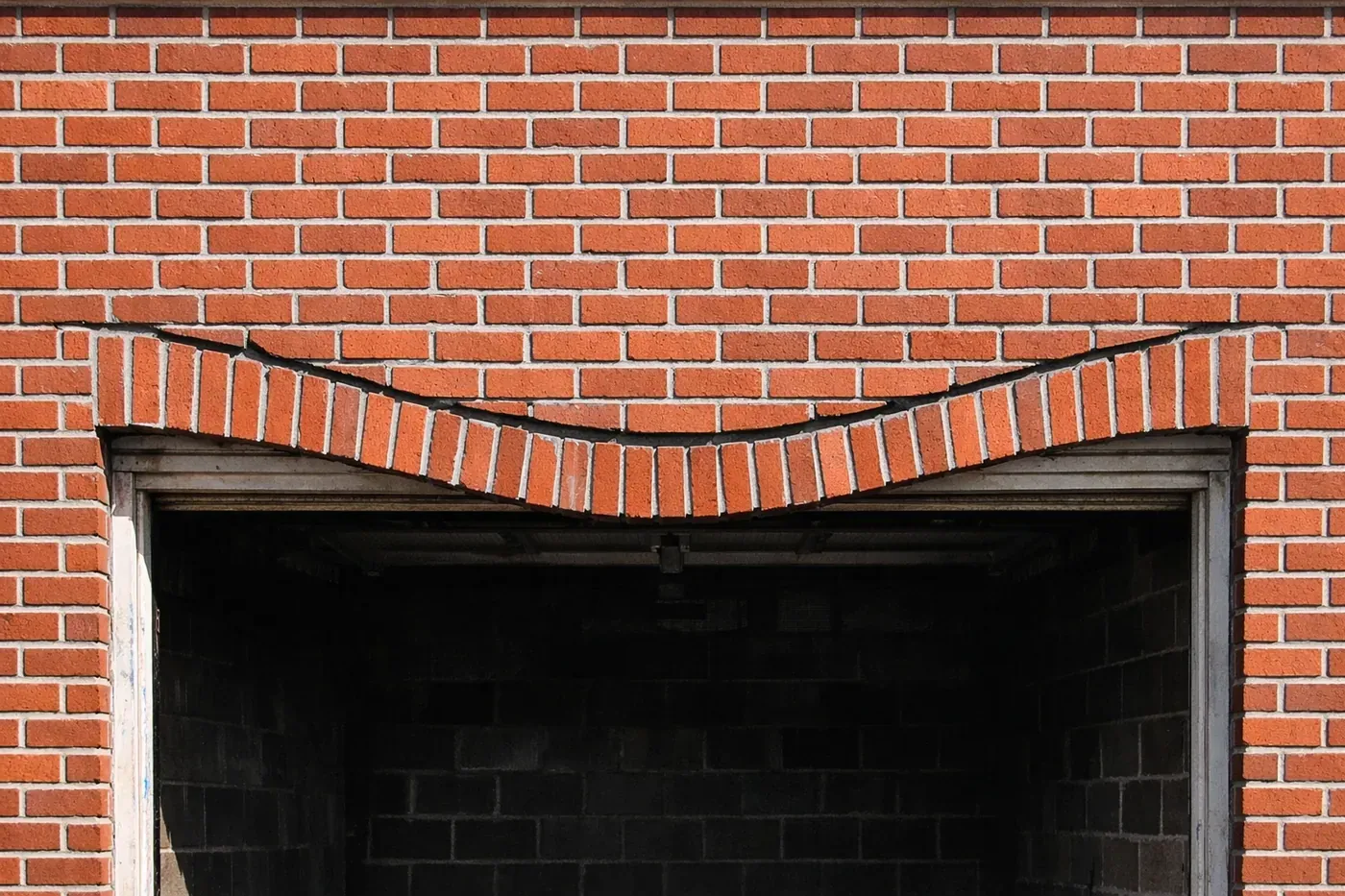 Sagging brick lintel above garage door showing center deflection